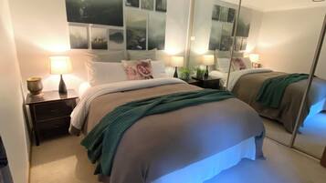 A hotel room with a large bed, two bedside tables with lamps, a mirror, and a wall with framed pictures.