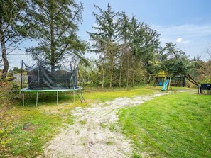 Enjoy a fun-filled stay with a backyard featuring a trampoline and swing set, surrounded by trees and a grassy area.