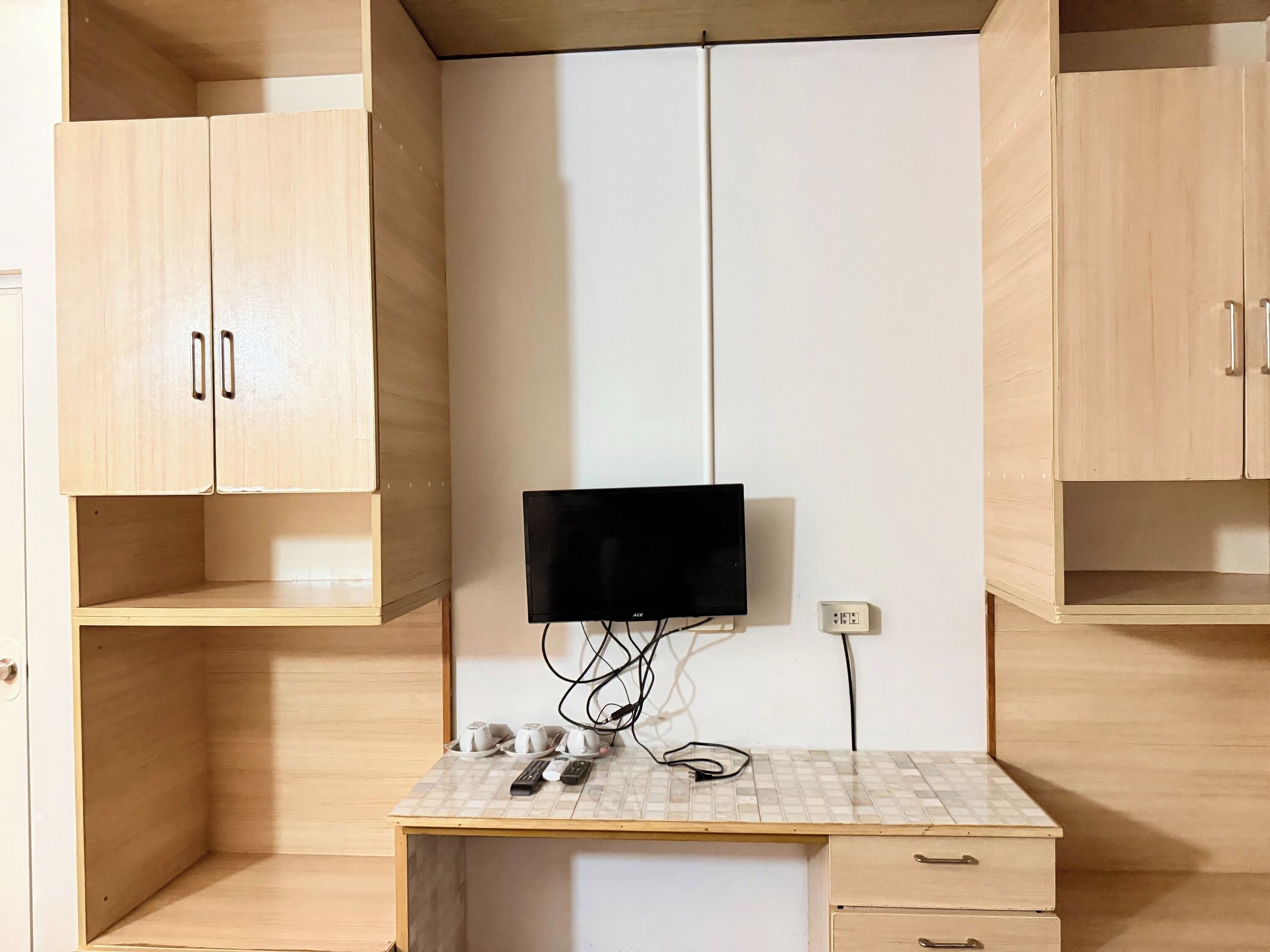 Une pièce avec un bureau en bois, un téléviseur fixé au mur et un comptoir recouvert de carreaux.