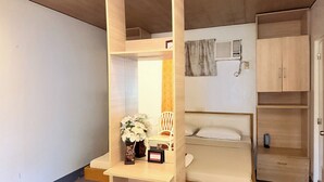 A compact room with a bunk bed, a small desk with a vase of flowers, a chair, and a cabinet.