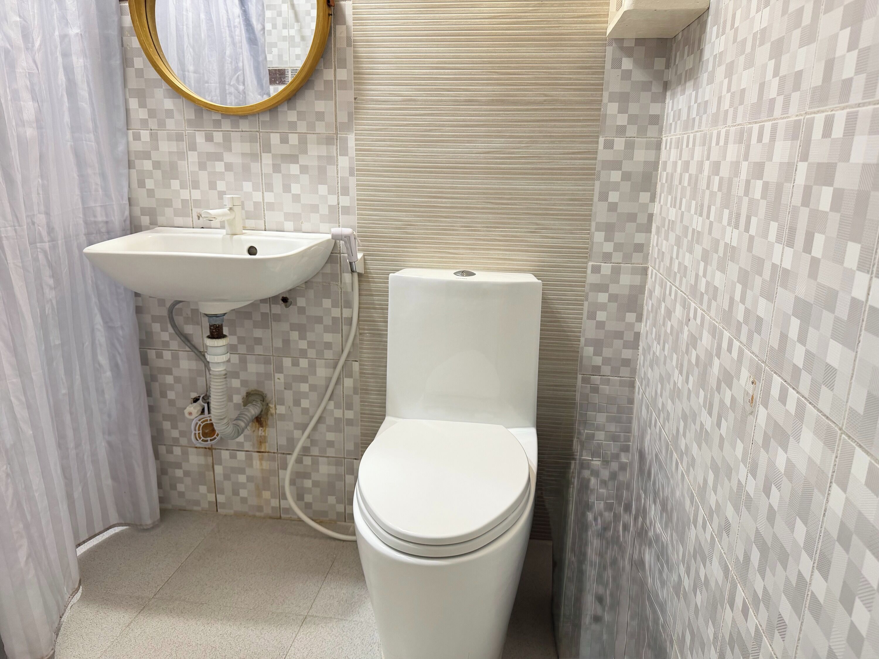 Un baño pequeño con lavamanos blanco, inodoro y paredes de azulejos.