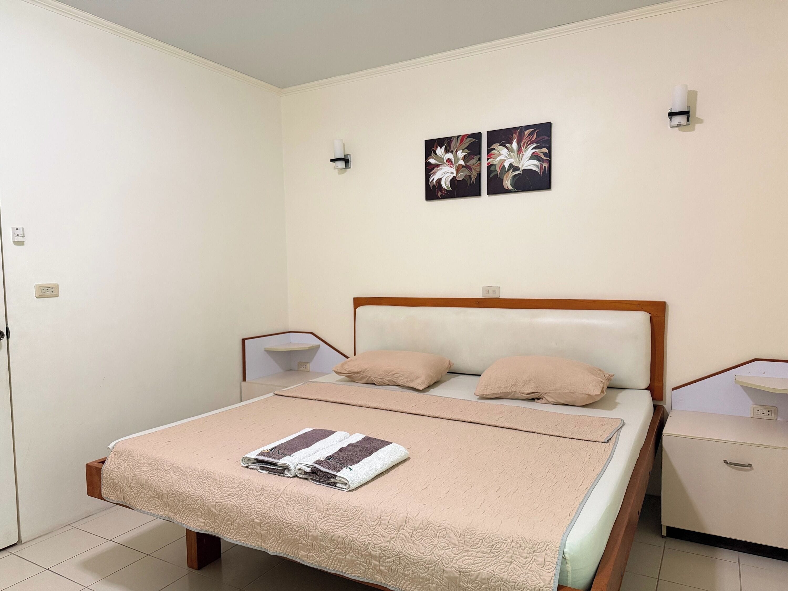 A neatly arranged bedroom with a bed, bedside tables, and two wall-mounted light fixtures.