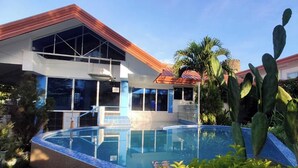 A modern building with a swimming pool, large windows, and a red roof.