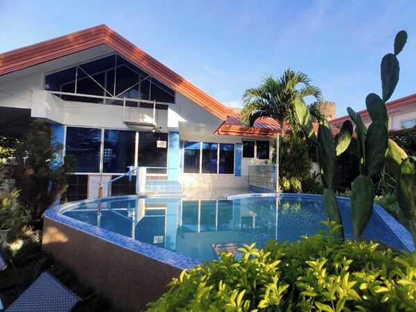 A modern building with a swimming pool, large windows, and a red roof. - Seaview Beach Resort Dumaguete Beachfront (Sibulan)