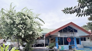 A building with a red roof, large windows, and a swimming pool.