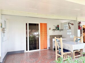 A room with a tiled floor, a sliding glass door, a table with chairs, a shelf with decorative items, and a fire extinguisher. - Seaview Beach Resort Dumaguete Beachfront (Sibulan)