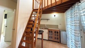 A kitchen with wooden cabinets, a sink, and a staircase leading to an upper level.