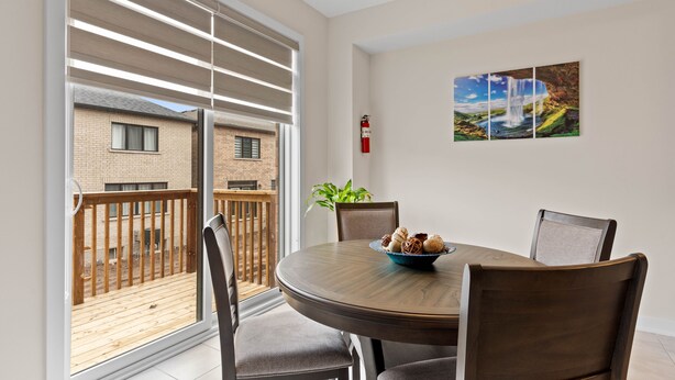 Een eetgedeelte met een ronde tafel, stoelen, een broodkom en een brandblusser aan de muur.