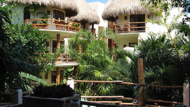 Un complexe hôtelier doté de bungalows aux toits de chaume, d’une végétation luxuriante et d’un espace piscine.