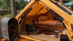 Een tent met een bed, een klein fornuis en een vloerkleed.