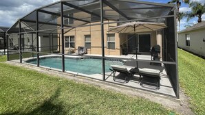 A covered outdoor swimming pool with lounge chairs and a patio area. - Spacious Villa with Private Heated Pool & Office (Kissimmee)