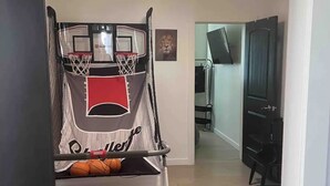 Un panier de basket avec un filet, un téléviseur fixé au mur et un tableau encadré accroché au mur.
