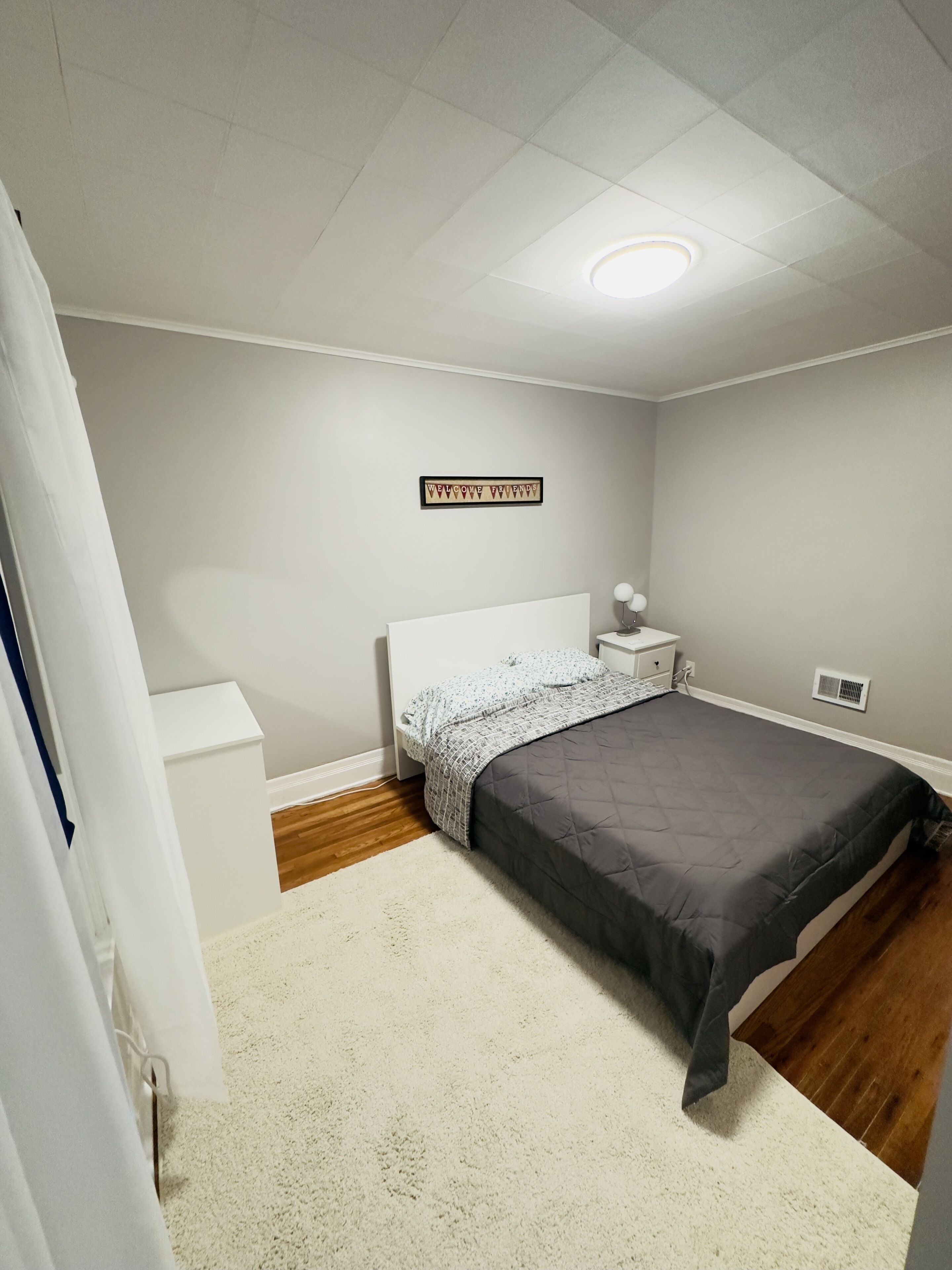 Une chambre à coucher avec un lit, une table de chevet et un panneau « Bienvenue » accroché au mur.