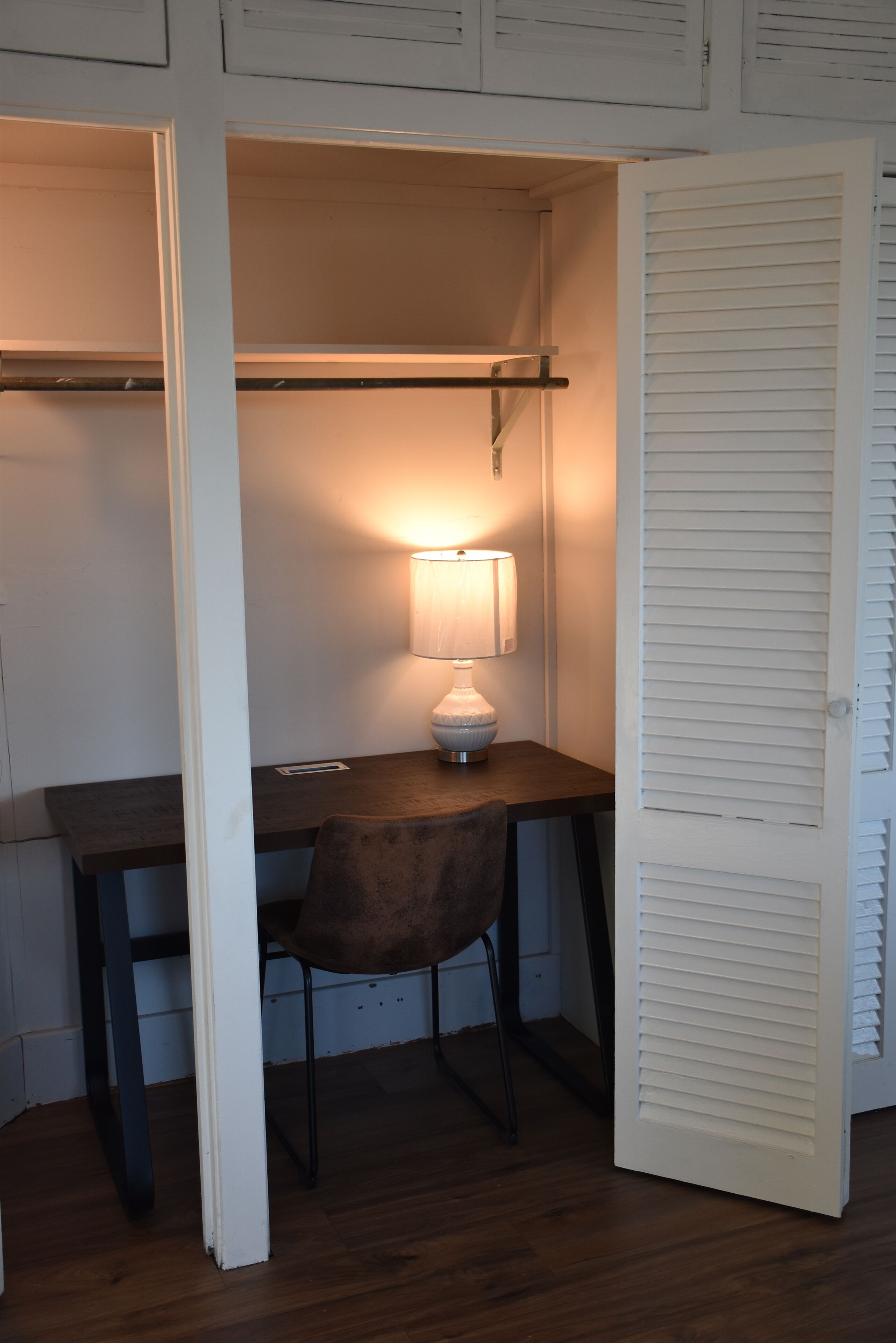 Un petit espace de travail clos, comprenant un bureau, une chaise et une lampe de table.