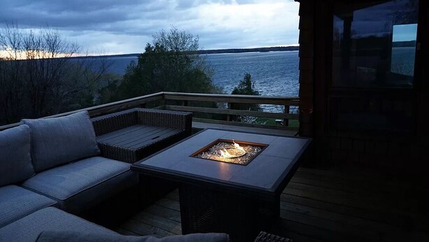 Een terras met vuurkorf, zitplaatsen en uitzicht op het water.
