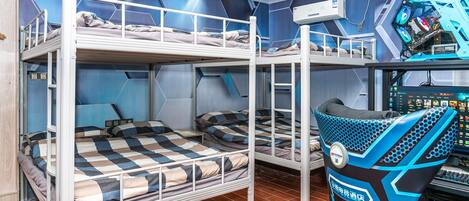 Une chambre avec un lit superposé, une chaise de jeu, un bureau avec un ordinateur et un climatiseur fixé au mur.