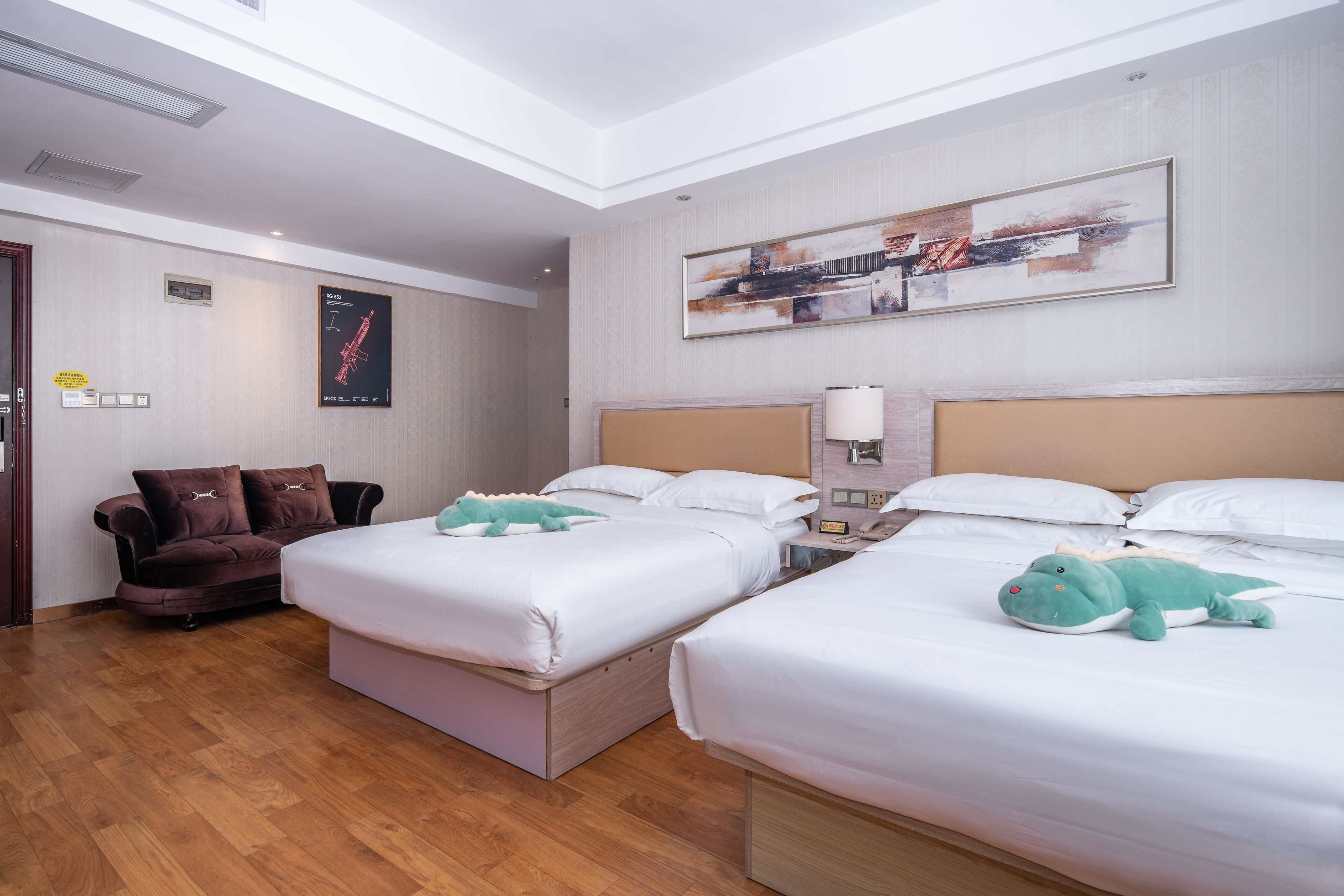 A hotel room with two beds, a sofa, and a painting on the wall.