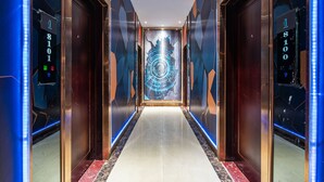A modern hallway with elevators, digital displays, and a geometric mural on the walls. - Baiyun Airport Grand Hyaat Airport Hotel - 24-hour Free Shuttle Bus (Guangzhou)