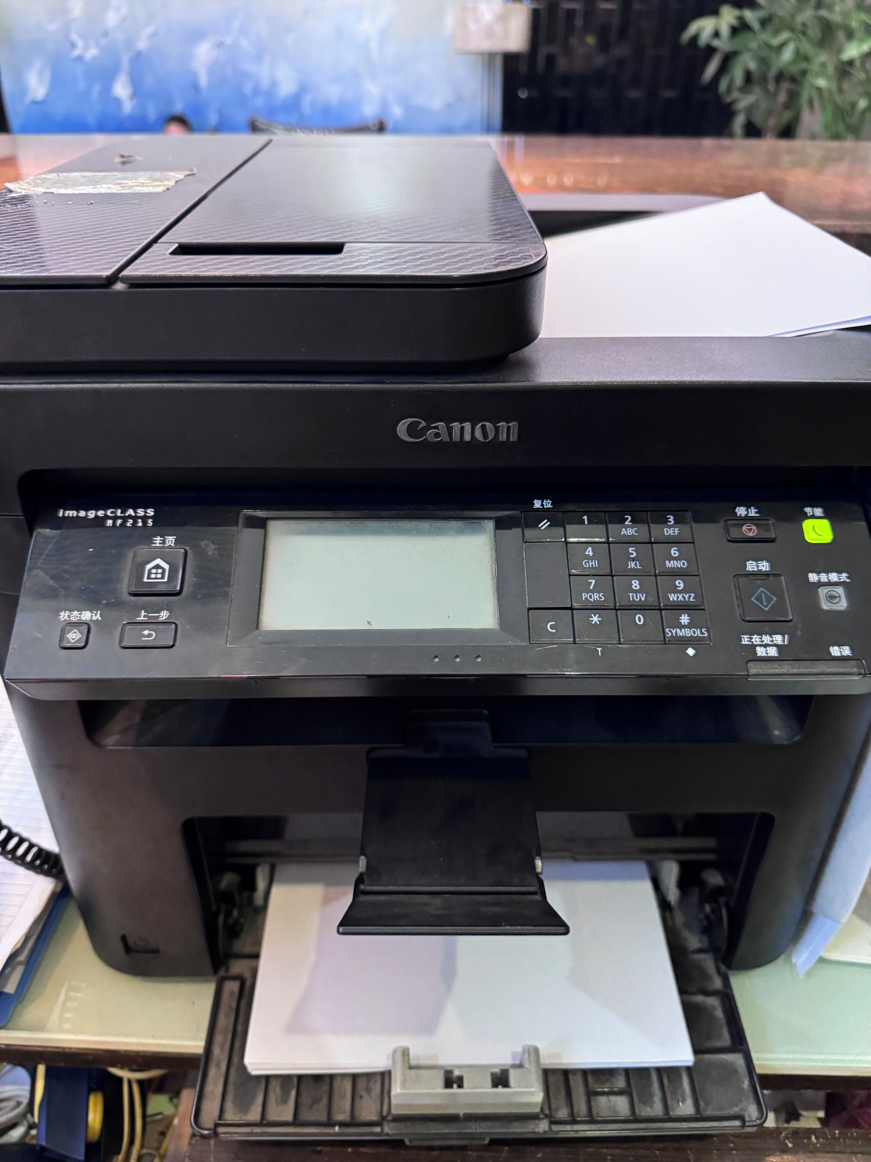 A Canon printer with a paper tray, control panel, and a document being printed.