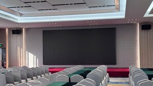 A conference room with rows of white chairs, a large screen, and a carpeted floor. - Baiyun Airport Grand Hyaat Airport Hotel - 24-hour Free Shuttle Bus (Guangzhou)