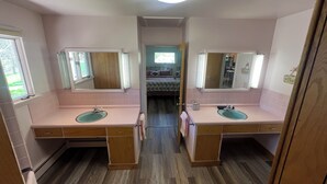 Un baño con dos lavamanos, armarios de madera y un espejo.