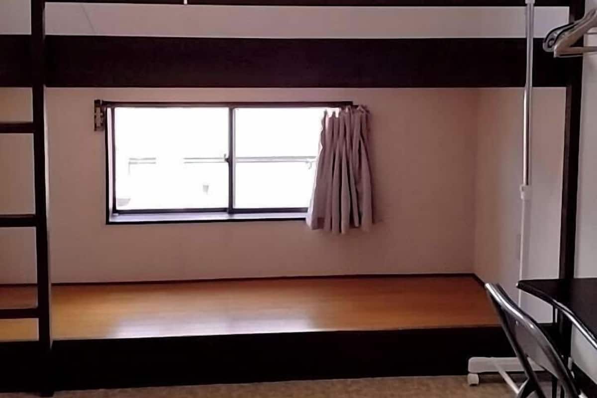 A bunk bed room with a window, a desk, and a chair.