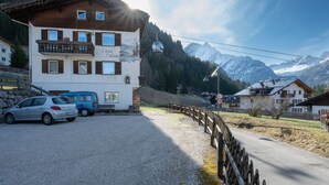 En toetages bygning med balkon, skilift i baggrunden og et bjerglandskab.