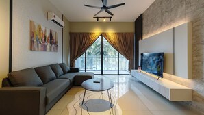 A modern living room with a sectional sofa, a round coffee table, a flat-screen TV, and a large window with curtains.