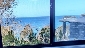 A window with a view of the sea and a building. There are two blue cups on a tray on a window sill. - Crow`s Nest - Couples Retreat (Eaglehawk Neck)