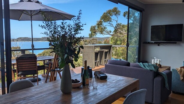 A modern living room with a large window overlooking a scenic view of the sea. - Crow`s Nest - Couples Retreat (Eaglehawk Neck)