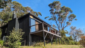 A modern wooden cabin with a balcony, surrounded by trees. - Crow`s Nest - Couples Retreat (Eaglehawk Neck)