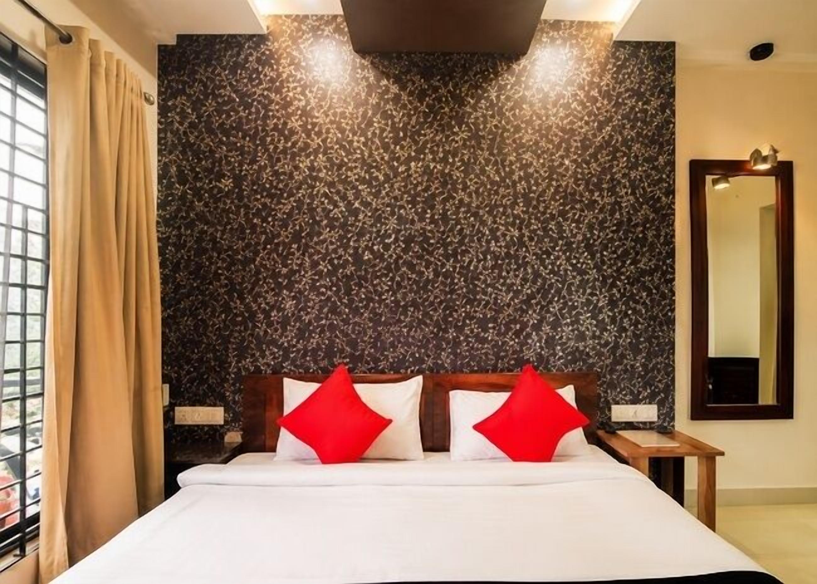 Une chambre d’hôtel avec un grand lit, un mur à la texture sombre, une fenêtre avec des rideaux et un miroir sur le mur.