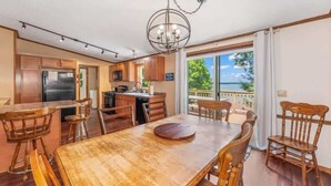 Une cuisine spacieuse avec des meubles de rangement en bois, une table à manger avec des chaises et une vue sur l’extérieur.