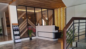 A modern reception area with a wooden ceiling, a reception desk, a staircase, and patterned flooring. - Regenta Inn Grand Koramangala  (Bengaluru)