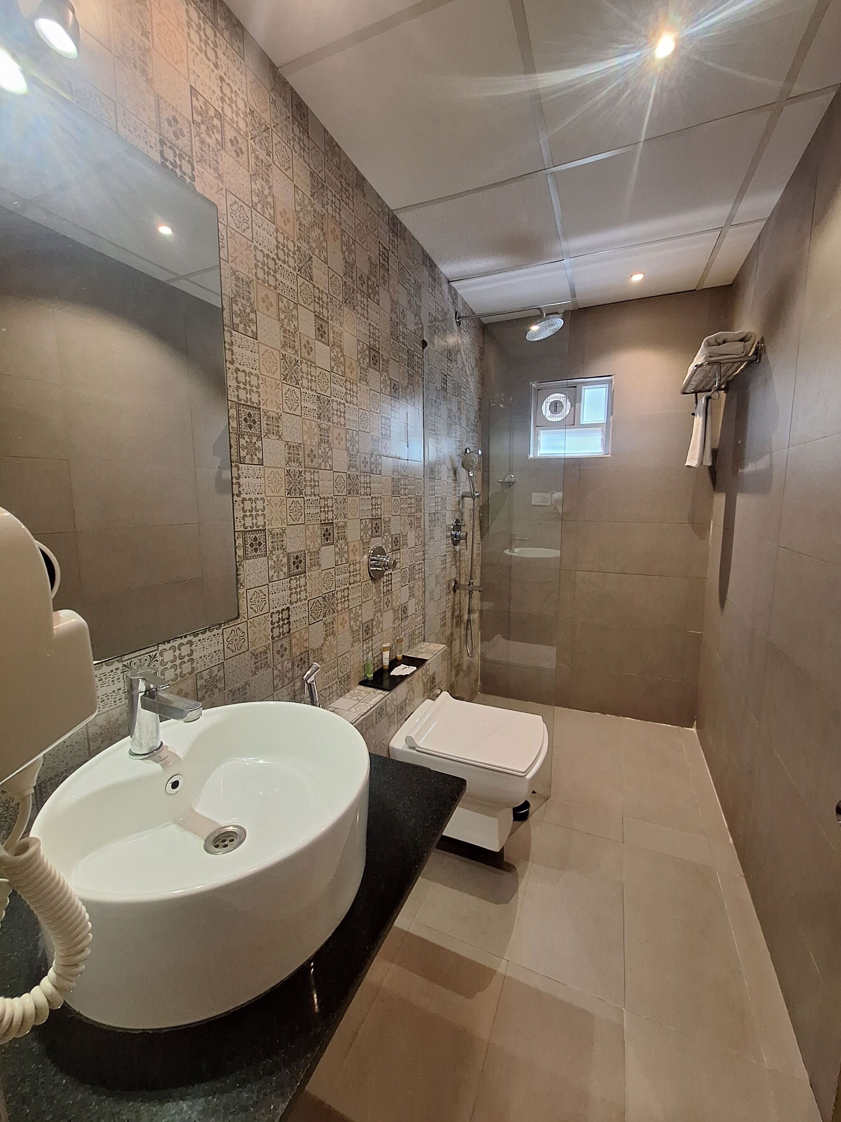 Un bany modern amb un gran lavabo rodó, un vàter i una zona de dutxa.