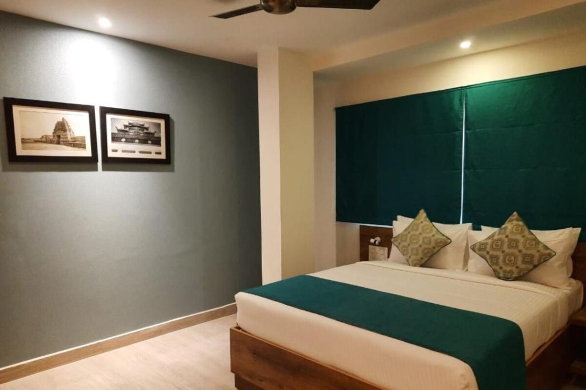 A bedroom with a bed, a ceiling fan, and two framed pictures on the wall.
