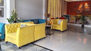 A spacious lobby with yellow sofas, a patterned floor, and a decorative wall. - Regenta Inn Grand Koramangala  (Bengaluru)