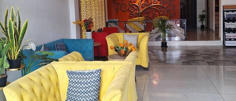 A spacious lobby with yellow sofas, a decorative wall, and a modern air conditioning unit.