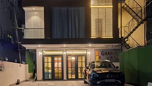 A building with a modern facade, a car parked in front, and a sign that reads "GRANA VISTA". - Regenta Inn Grand Koramangala  (Bengaluru)