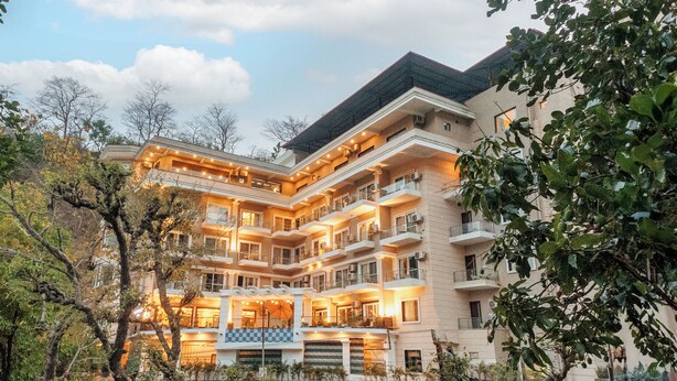 Un hotel de varios pisos con balcones, un piso con diseño de cuadros y una fachada bien iluminada.