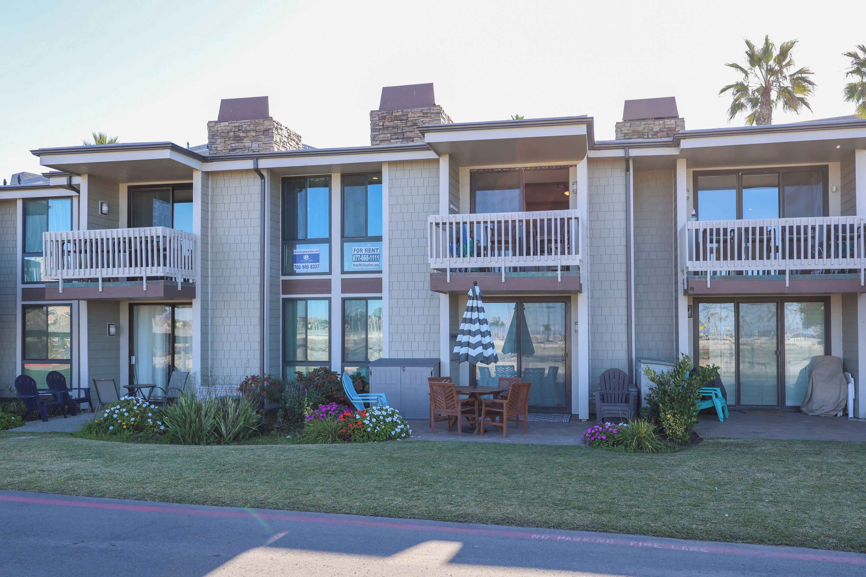 A multi-story hotel with balconies, outdoor seating, and a garden area.