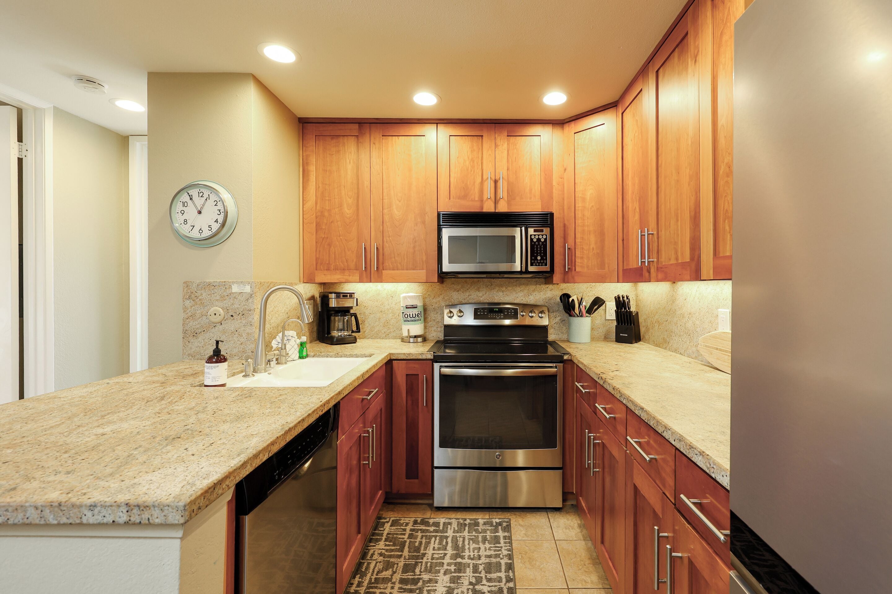 A modern kitchen with wooden cabinets, stainless steel appliances, and a granite countertop.