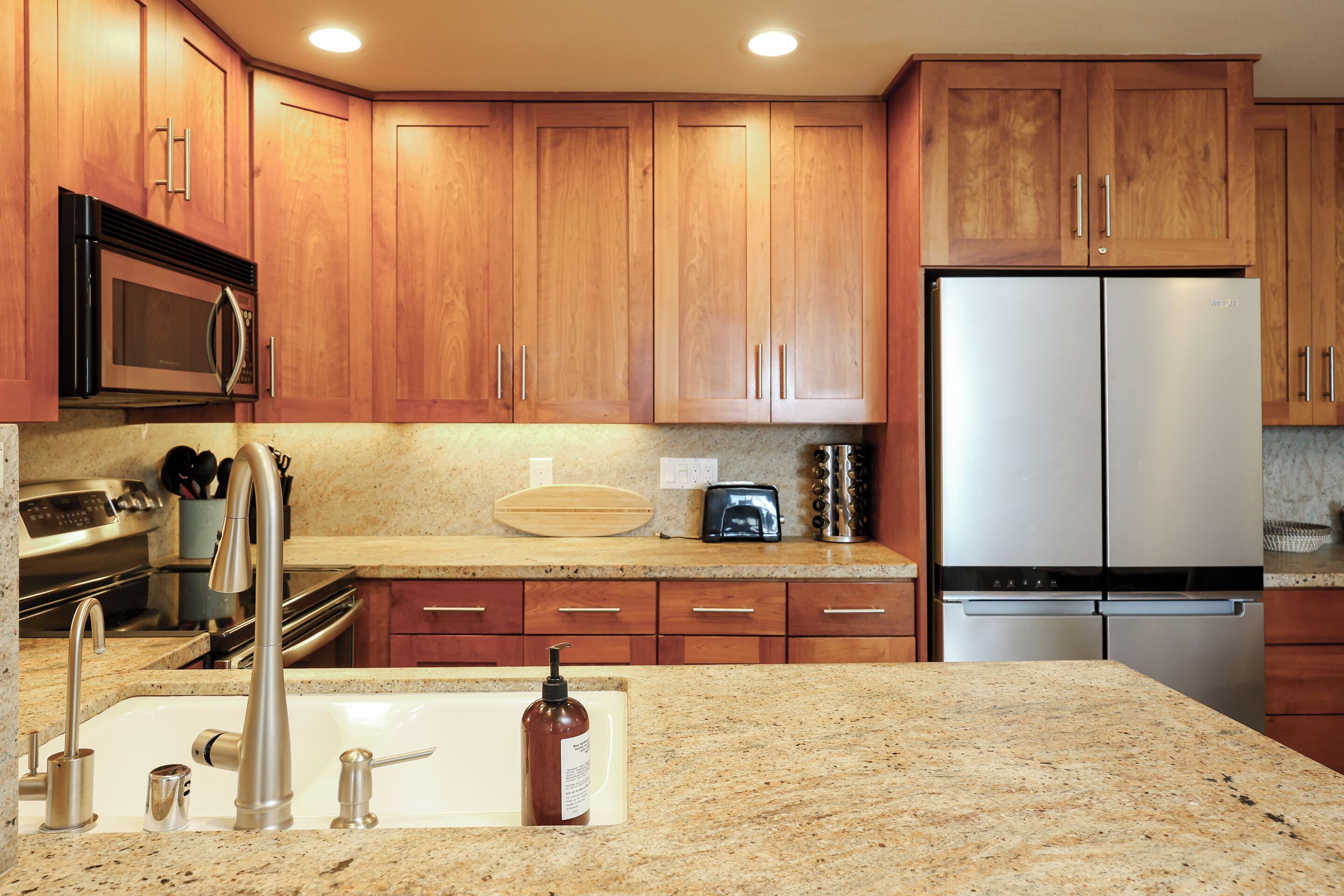 A kitchen with wooden cabinets, stainless steel appliances, granite countertops, and a double sink.
