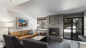 Un salon moderne avec une cheminée, des murs en briques blanches et une grande fenêtre.