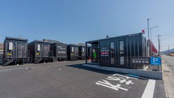 Un bâtiment moderne avec une enseigne indiquant l’hôtel « The Yard », un panneau de signalisation pour le parking et un ciel dégagé.