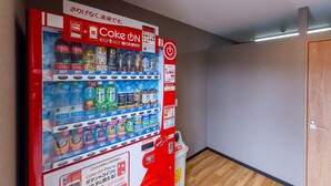 A vending machine with various drinks and snacks, a Coca-Cola sign, and a target sign on the wall. - HOTEL R9 The Yard Sakuragawa (Sakuragawa)