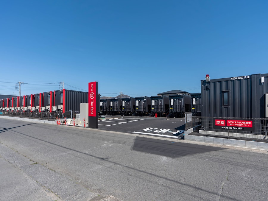 A row of hotel containers with a clear sky and a sign indicating a hotel named "The Yard."