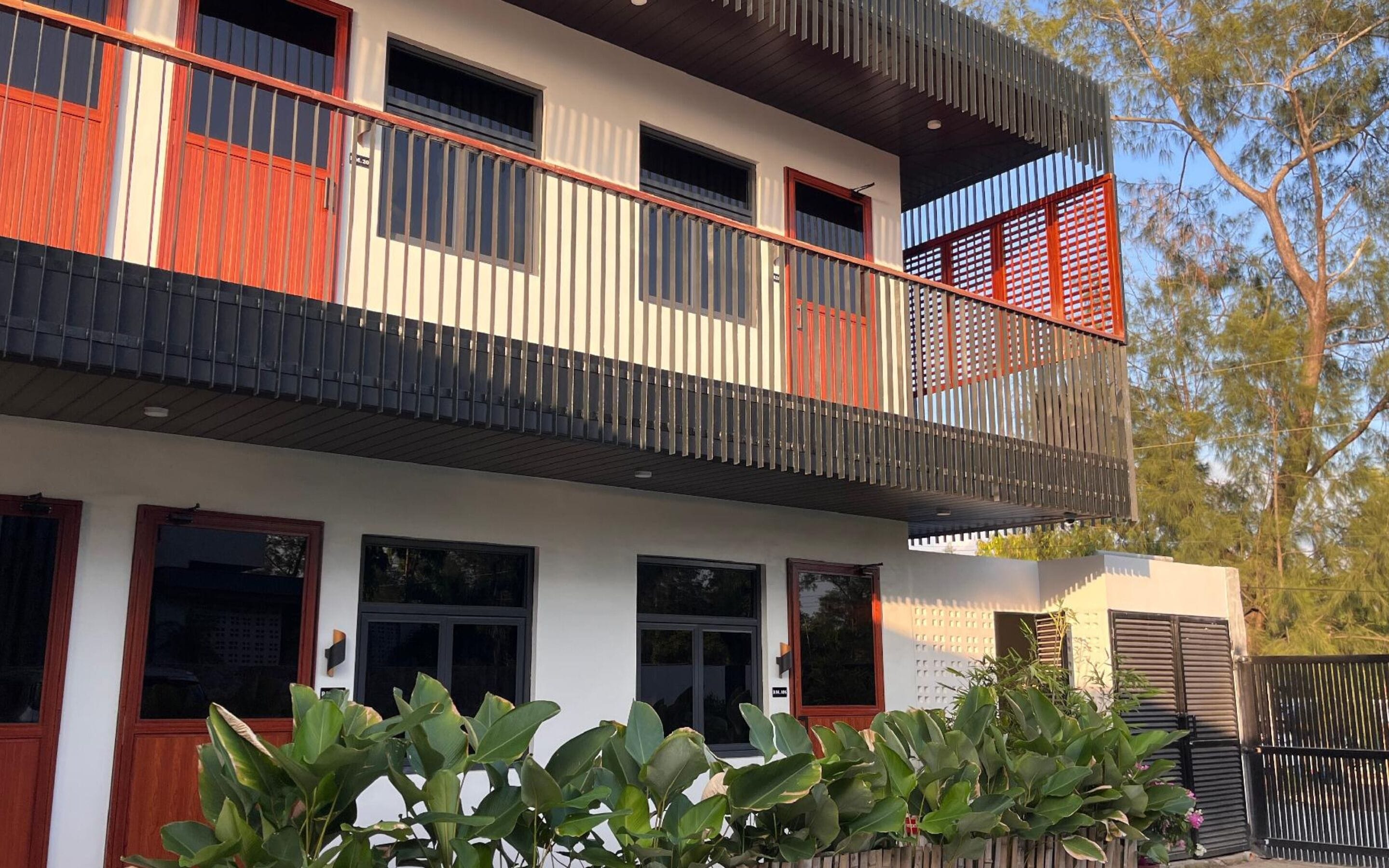 A modern two-story building with a balcony, large windows, and a gated entrance.