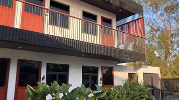 A modern two-story building with a balcony, large windows, and a gated entrance.