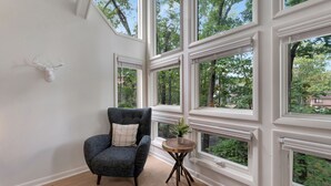 A room with large windows, a chair, and a small table with a plant.